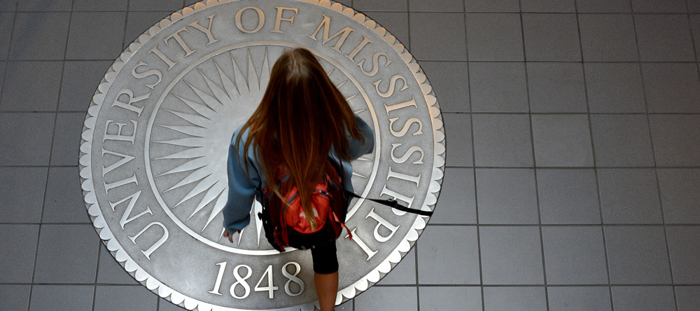 A student walks across the seal of The University of Mississippi